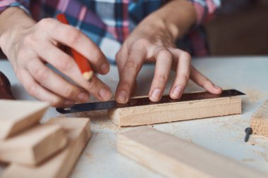 Marangoz elleri tahta bir kalemle ölçü alıyor. Diy ahşap işçiliği ve mobilya yapımı kavramı