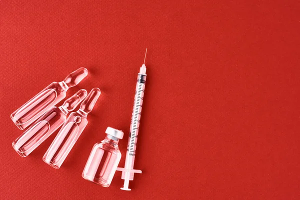 Syringes and medicine bottles with medication on a red background, top view with copy space — 스톡 사진