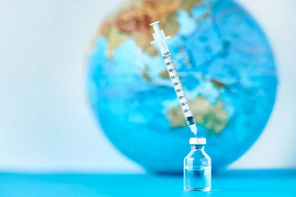 Medical syringe and ampoule with a medicine against Earth globe. Virus threat and epidemic protection concept — 스톡 사진