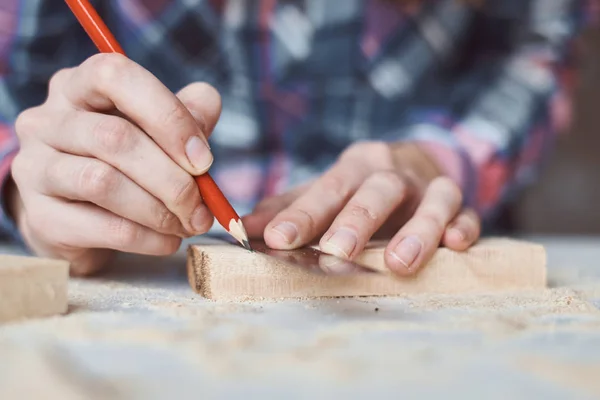 stock image Carpenter hands taking measurement with a pencil of wooden plank. Concept of DIY woodwork and furniture making