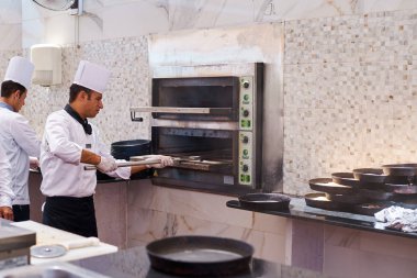 Aşçı mutfaktaki fırından fırından pizza aldı.
