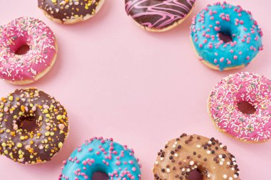 Rengarenk donörlerin çerçevesi dekore edilmiş süslemeler ve pastel pembe arka planda krema, üstten düz görünüm