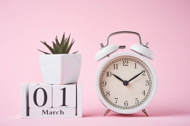Kırmızı arkaplanda beyaz alarm saati ve ahşap takvim bl