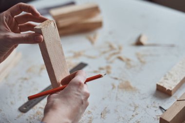 Marangoz elleri tahta bir kalemle ölçü alıyor. Diy ahşap işçiliği ve mobilya yapımı kavramı