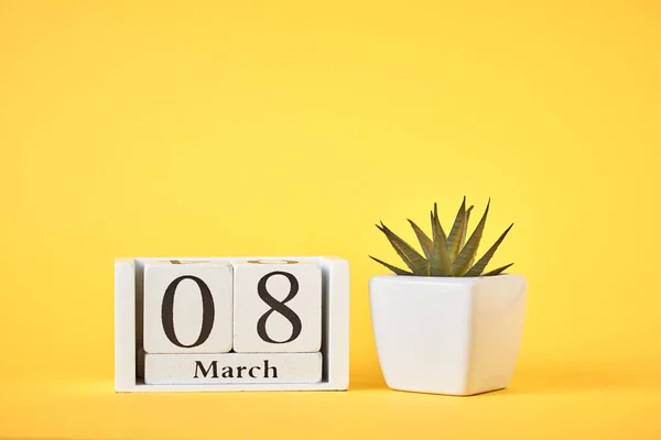 Women's Day concept. Wooden calendar block with date 8 march and plant on the yellow background with copy space — 图库照片