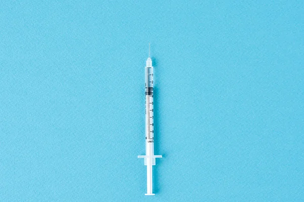 Medical syringe on the blue background, top view with copy space. Vaccination and virus protection concept — 스톡 사진