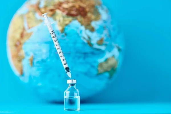 Medical syringe and ampoule with a medicine against Earth globe. Virus threat and epidemic protection concept — 스톡 사진
