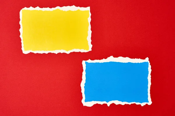 Two ripped paper torn edge sheets on a red background. Template with piece of color paper