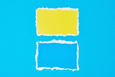 Mavi arka planda iki yırtık kağıt var. Renk kağıdıyla şablon