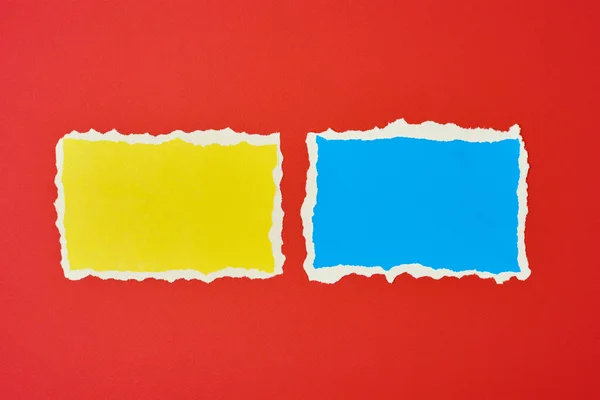 Two ripped paper torn edge sheets on red background. Template with piece of color paper