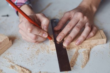 Marangoz elleri tahta kalemle ölçü alıyor. Diy ahşap işçiliği ve mobilya yapımı kavramı