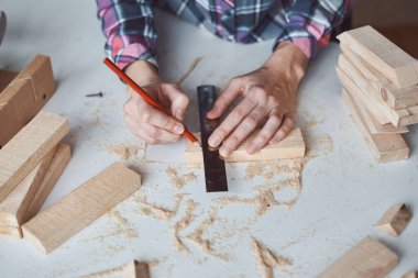 Marangoz elleri tahta kalemle ölçü alıyor. Diy ahşap işçiliği ve mobilya yapımı kavramı