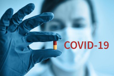 Koruyucu maskeli kadın elinde ilaç tutuyor. Coronavirus problemi ve covid-19 koruma kavramı
