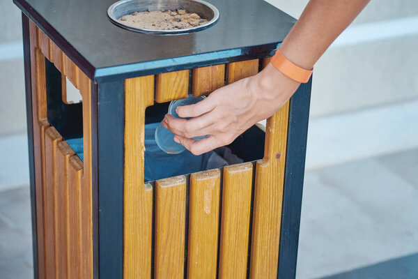 Woman hand throwing plactic cup for water in trash bin