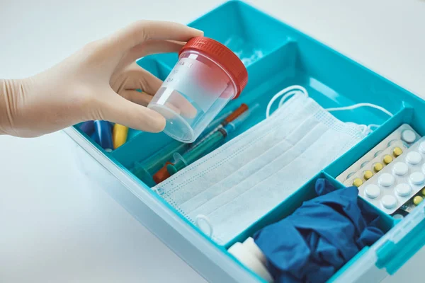 Hands in medical gloves take a test cup from medicine box. Healthcare and medicine concept. First aid kit