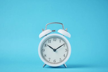 Vintage white alarm clock on blue backround with copy space. Time concept