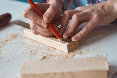 Marangoz elleri tahta kalemle ölçü alıyor. Diy ahşap işçiliği ve mobilya yapımı kavramı