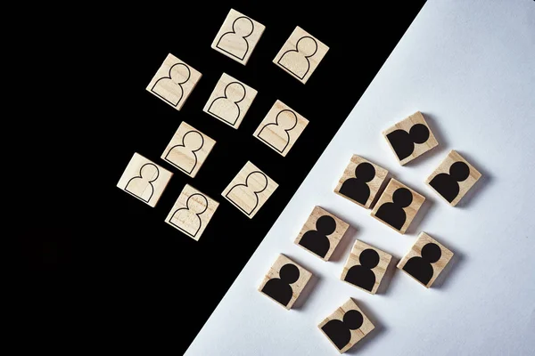 Concept of racism and misunderstanding between people, prejudice and discrimination. Wooden block with white people figures and black mans separated, top view