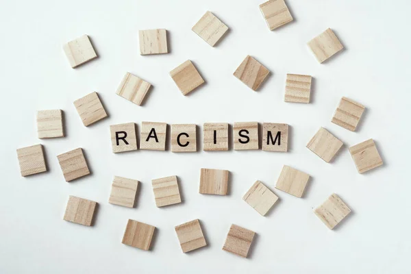 Concept of racism and misunderstanding between people, prejudice and discrimination. Wooden block with word racism on white backround