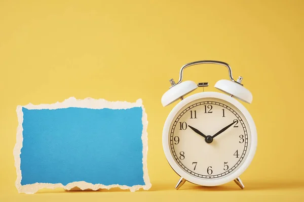 Beyaz Klasik Alarm Saati Sarı Zemin Üzerinde Mavi Yırtık Kağıt — Stok fotoğraf
