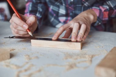 Marangoz elleri tahta kalemle ölçü alıyor. Diy ahşap işçiliği ve mobilya yapımı kavramı