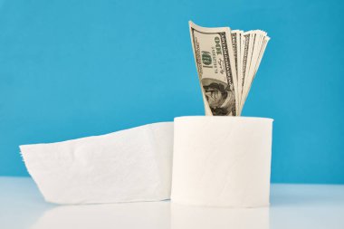 Panik Covid-19 Coronavirus salgını konseptini satın alıyor. Mavi arka planda Amerikan dolarları olan tuvalet kağıdı rulosu.. 