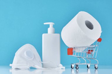 Tuvalet kağıdı rulosu, antiseptik jel ve mavi arka planda koruyucu maske. İnsanlar ev karantinası için gerekli şeyleri stokluyorlar. Coronavirus covid-19 konsepti paniği satın alan tüketici. 