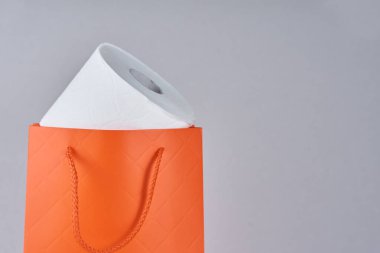Gri arka planda hediye olarak alışveriş poşetinde tuvalet kağıdı rulosu.