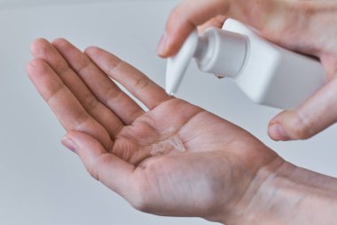 COVID-19 salgını antiseptik içeren sağlık koruma kavramı. Koronavirüs için önlem olarak dezenfektan ya da antiseptik jel kullanan kadın ellerini yıkıyor.