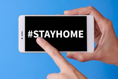 Virüse karşı korunmak için koronavirüs salgını sırasında evde kalmalarını söyle. Covid-19 salgını. Akıllı telefondaki parmak dokunuşu etiketli Evde kal