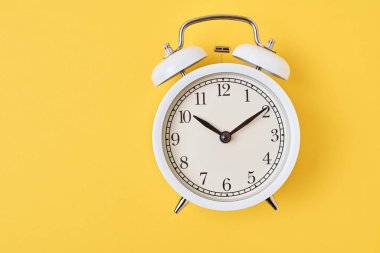 Sarı arka planda, kopyalama alanı olan beyaz alarm saati. Zaman kavramı