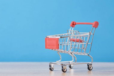 Mavi arka planda boş alışveriş arabası. Alışveriş konsepti