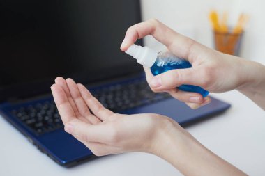 Coronavirus covid-19 salgınından korumak için dezenfeksiyon aleti. Bilgisayarda çalışmadan önce antibakteriyel antiseptik dezenfektanla el temizleme.