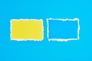 Mavi arka planda iki yırtık kağıt var. Renk kağıdıyla şablon