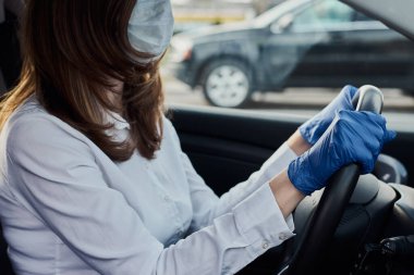 Koruyucu maskeli ve ilaç eldivenli bir kadın araba kullanıyor. Coronavirus covid-19 koruma kavramı