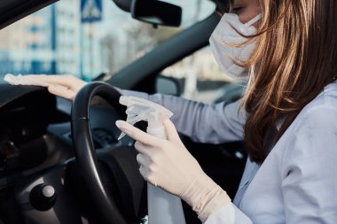 Koronavirüsten korumak için dezenfeksiyon spreyiyle araba temizleyen kadın. Araba yıkama