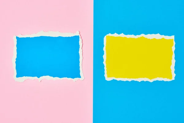 Two ripped paper torn edge sheets on blue and pink background. Template with piece of color paper