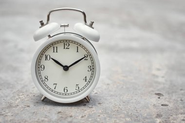 Gri arka planda beyaz antika çalar saat. Üretim denetimi ve görev planlama kavramı