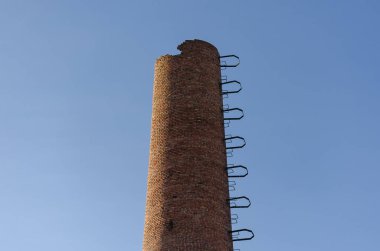 Yok edilmiş fabrika bacası. Mavi gökyüzüne karşı kırmızı tuğla boru.