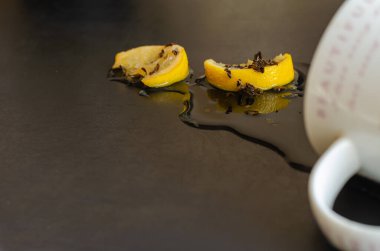 Tepetaklak olmuş fincanlar ve dökülen çayın geri kalanı koyu bir masada..