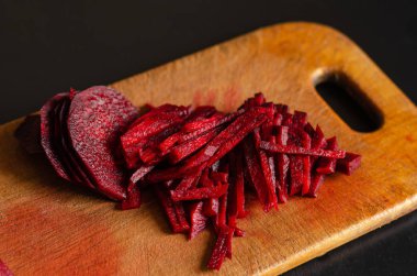 Kesme tahtasında çiğ pancar. Taze pancar kökü parçalanmış. Yemek yapmak için gerekli malzemeler. Seçici odaklanma. İnsanlar olmadan. Yakın plan.