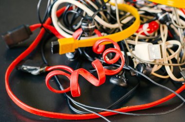 Karanlık arka planda bir sürü kablo ve kablo var. Bir sürü renkli kablo kablosu şarjı, kablo prizi ve Usb yığını. Yeniden Kullanım ve Geri Dönüşüm konsepti. Seçici odak. 