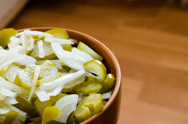 Pickled cucumbers with raw onion slices in a clay bowl on the le — Stock Photo, Image