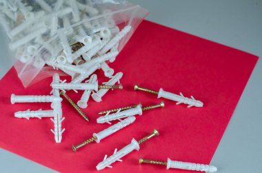 Kırmızı arkaplanda plastik kapaklı vidalar.