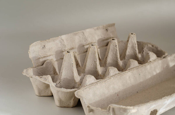 Empty cardboard egg tray. Tray for ten chicken eggs on a white background. Stop plastic. Side view. Selective focus. Close-up.