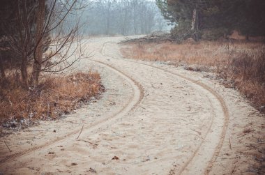 Kumlu bir yolda tekerlek izleri. Virajın arkasına gizlenen dolambaçlı bir yol var. Off-road seyahati. Seçici odaklanma. İnsanlar olmadan.