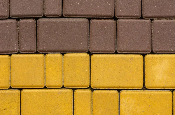 Cement blocks of different colors. Blocks of paving tiles of various sizes and sizes are yellow and brown. Multitask background. Shooting outdoors. Selective focus. Close-up.