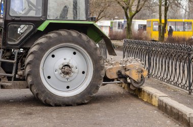Asfalt yerine değirmen keskisi olan bir traktör. Arka monte edilmiş değirmen kesici. Şehir hayatı. Yan görüş. Seçici odaklanma. Açık havada çekim..