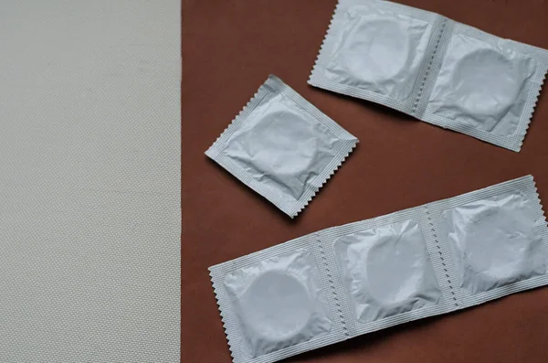 Condooms in verpakking op een bruine achtergrond. — Stockfoto