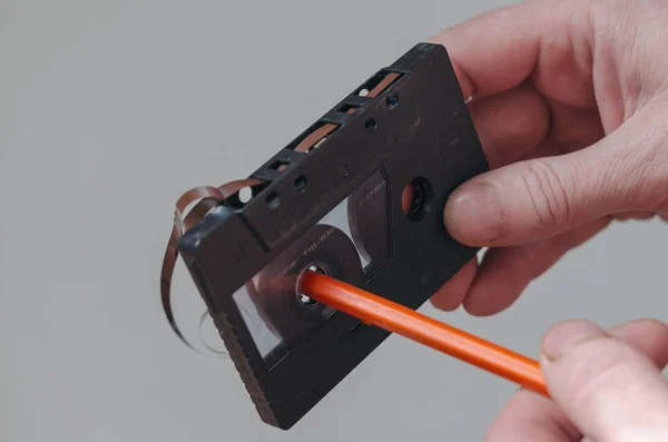 Close-up of a male hand with an old audio cassette and a pencil. — 스톡 사진